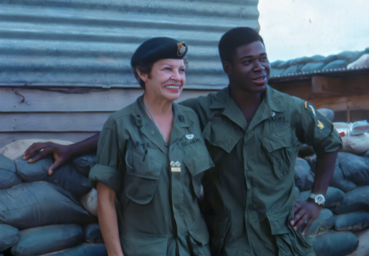 Lt. Col Martha “Maggie” Raye, honorary Green Beret, with SP4 Lewis Chapman, Jr., in front of the A-325’s Team House. Nicknamed “Colonel Maggie” by the troops, she went out to border camps where no other “VIPs” would be allowed. (Photo courtesy Lew Chapman)